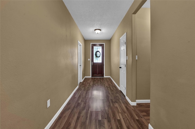 doorway with dark wood-type flooring and a textured ceiling