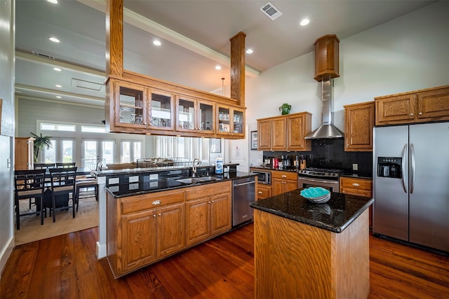 kitchen with a kitchen island, appliances with stainless steel finishes, dark stone countertops, and kitchen peninsula