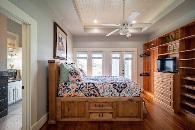 bedroom featuring wood ceiling, ensuite bath, hardwood / wood-style floors, a tray ceiling, and access to outside