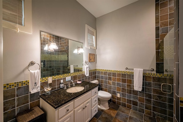 bathroom with tile walls, vanity, toilet, and walk in shower