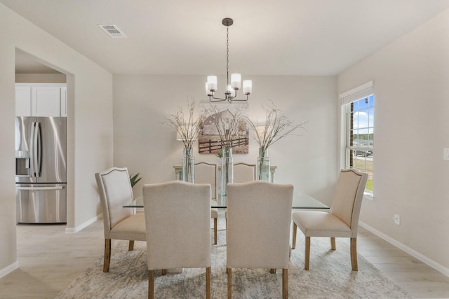 dining space featuring light wood-type flooring and an inviting chandelier