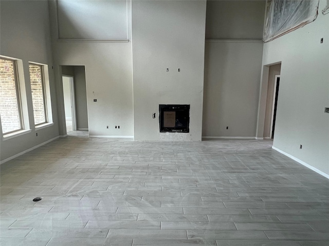 286 Peninsula Point Dr, Montgomery, TX 77356 - unfurnished living room featuring a towering ceiling, a fireplace, and wood finished floors