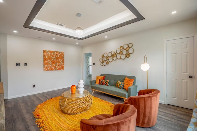 living room featuring dark hardwood / wood-style flooring and a tray ceiling