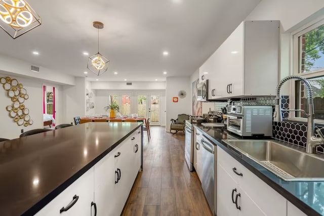 kitchen featuring sink, white cabinetry, hanging light fixtures, dark hardwood / wood-style flooring, and stainless steel appliances