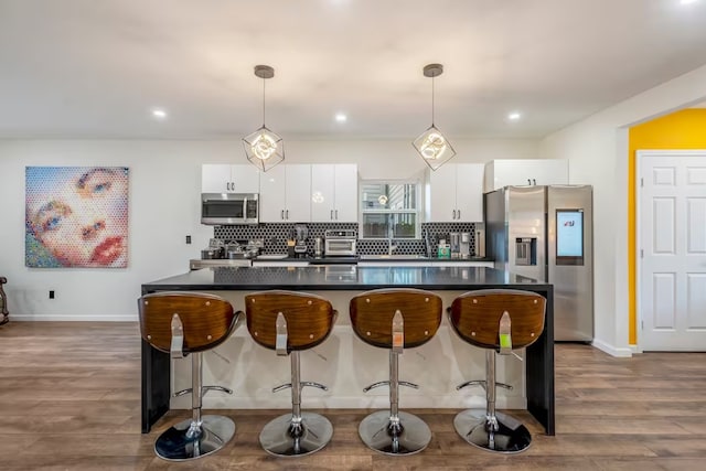 kitchen with tasteful backsplash, hanging light fixtures, appliances with stainless steel finishes, dark hardwood / wood-style floors, and white cabinets