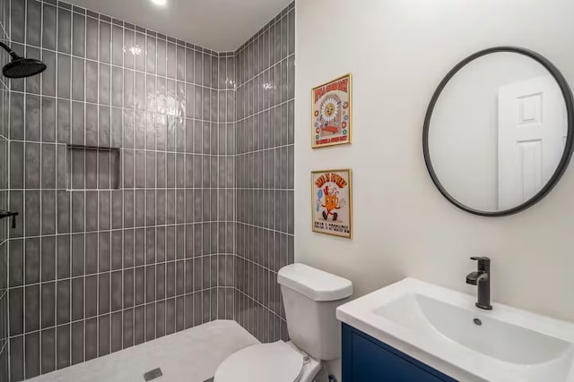 bathroom with vanity, tiled shower, and toilet