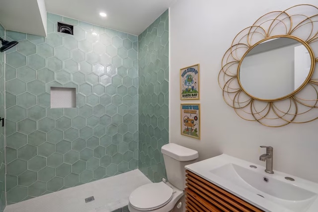 bathroom featuring vanity, toilet, and a tile shower