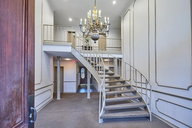 stairway with a notable chandelier, a towering ceiling, and carpet