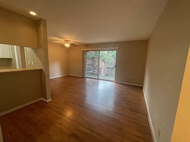 unfurnished living room with dark wood-style floors, baseboards, and a ceiling fan