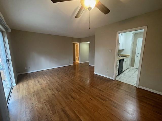 spare room with a ceiling fan, light wood-type flooring, and baseboards