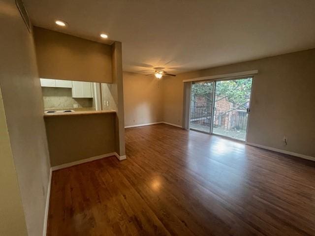 unfurnished living room featuring dark wood-type flooring and ceiling fan