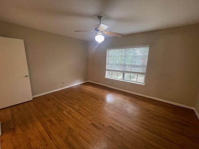 spare room featuring ceiling fan, dark wood-type flooring, and baseboards