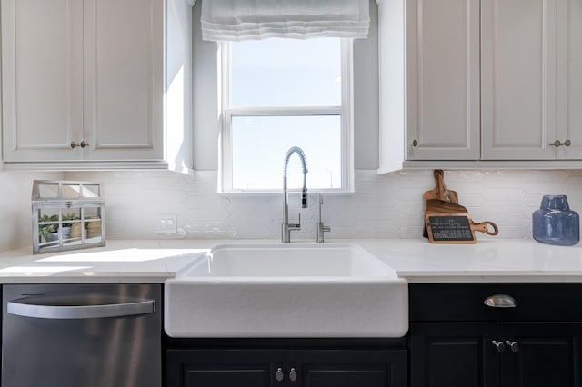 kitchen featuring backsplash, stainless steel dishwasher, dark cabinetry, and a sink