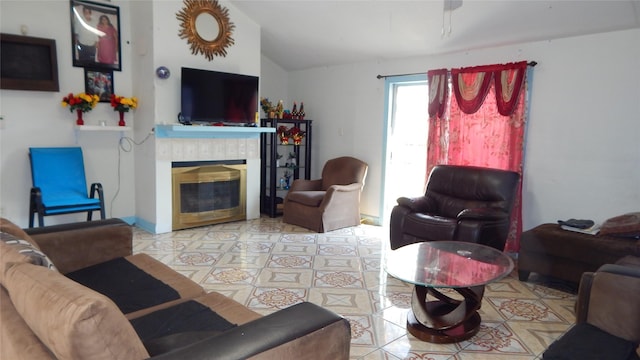 living room featuring lofted ceiling, a tiled fireplace, and light tile patterned flooring