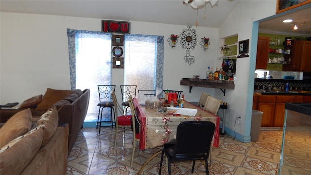 dining area with bar area, vaulted ceiling, and light tile patterned floors