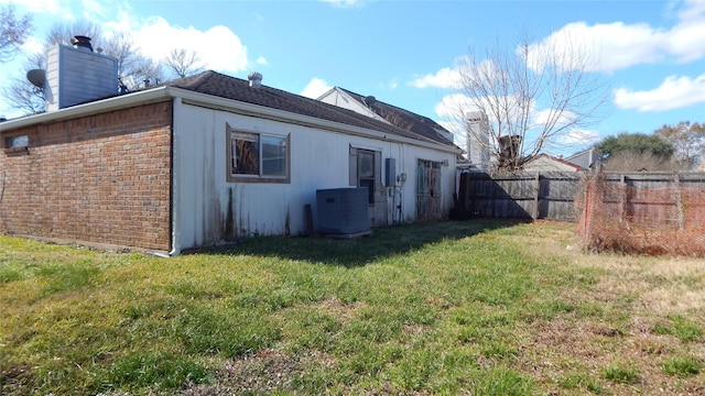 rear view of house with cooling unit and a yard