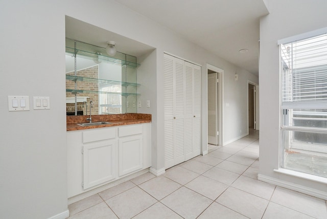 bar featuring white cabinetry, light tile patterned flooring, and sink