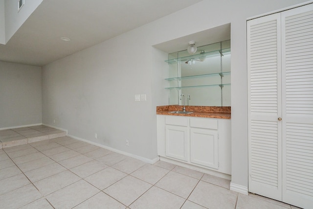 bar with white cabinetry, sink, and light tile patterned flooring