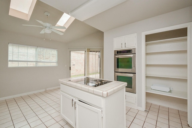 kitchen with light tile patterned floors, tile counters, stainless steel double oven, black electric stovetop, and white cabinets