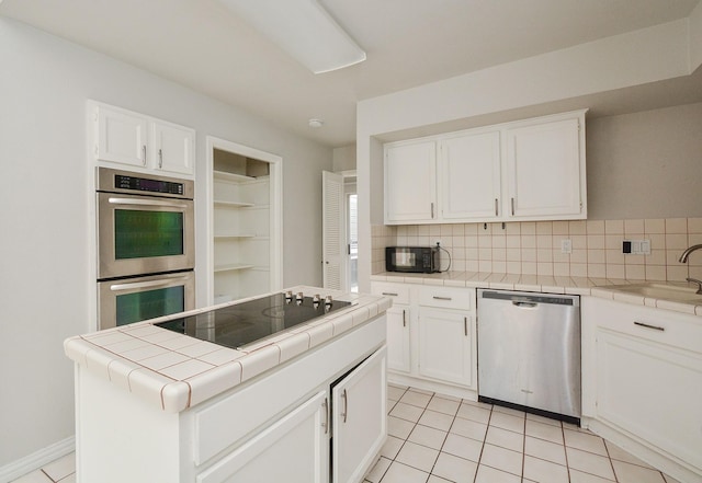 kitchen with white cabinets, tile countertops, a kitchen island, and black appliances