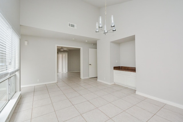 empty room featuring an inviting chandelier, light tile patterned floors, and a towering ceiling