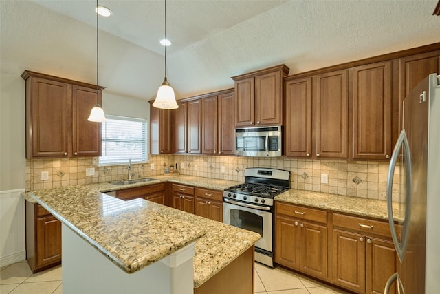 kitchen featuring appliances with stainless steel finishes, a kitchen island, sink, hanging light fixtures, and light stone countertops