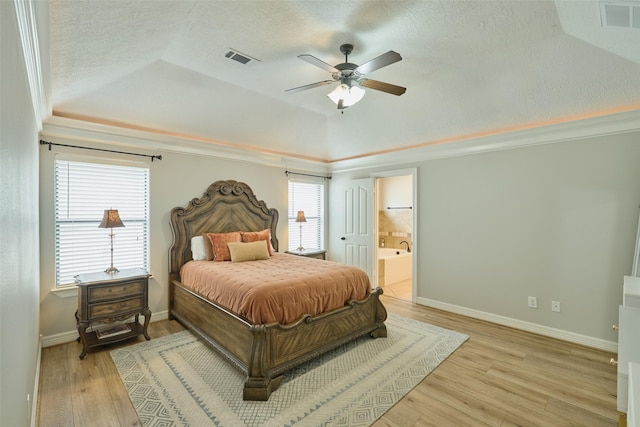 bedroom featuring connected bathroom, lofted ceiling, ceiling fan, light hardwood / wood-style floors, and a textured ceiling