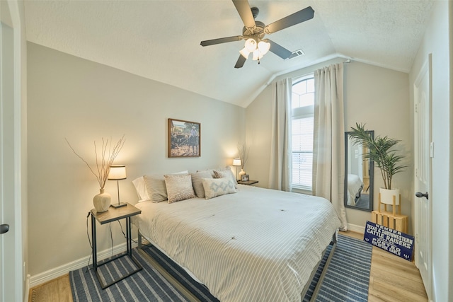 bedroom with vaulted ceiling, ceiling fan, light hardwood / wood-style floors, and a textured ceiling