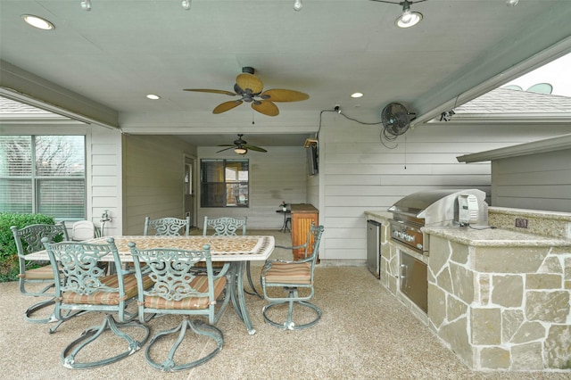 view of patio with area for grilling, a bar, ceiling fan, and an outdoor kitchen