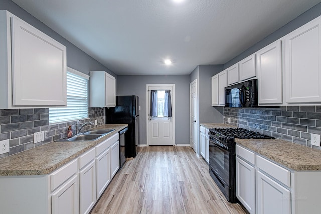 kitchen featuring white cabinets, a healthy amount of sunlight, sink, and black appliances