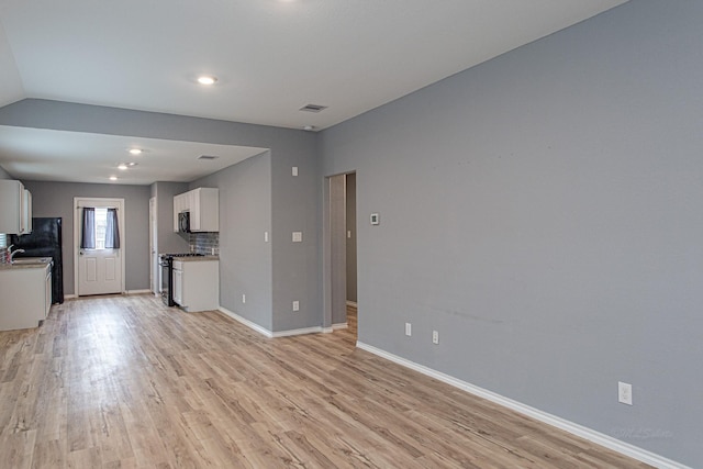 unfurnished living room featuring sink and light hardwood / wood-style flooring