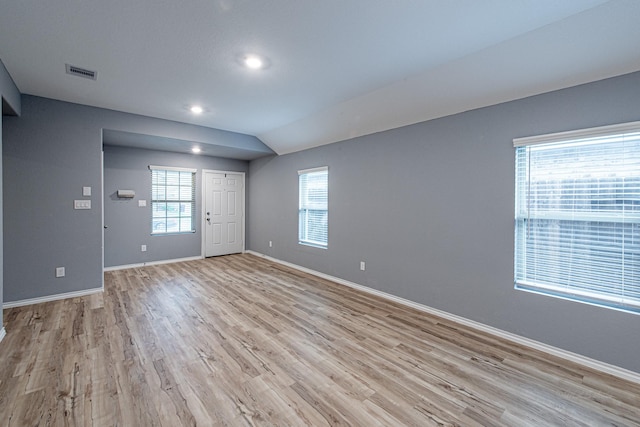 unfurnished room featuring lofted ceiling and light wood-type flooring