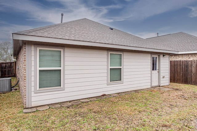 back of house with cooling unit and a lawn