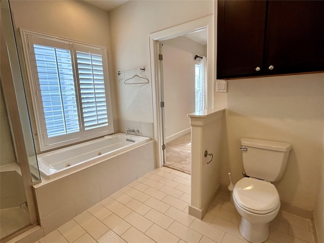 bathroom featuring tile patterned flooring, tiled tub, and toilet