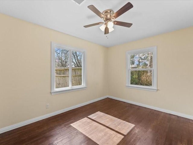 unfurnished room with ceiling fan, a wealth of natural light, and dark hardwood / wood-style flooring