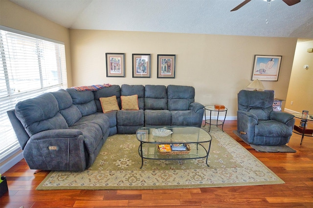 living room with ceiling fan, wood-type flooring, vaulted ceiling, and a textured ceiling