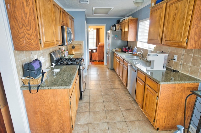 kitchen featuring sink, crown molding, stone countertops, light tile patterned floors, and appliances with stainless steel finishes