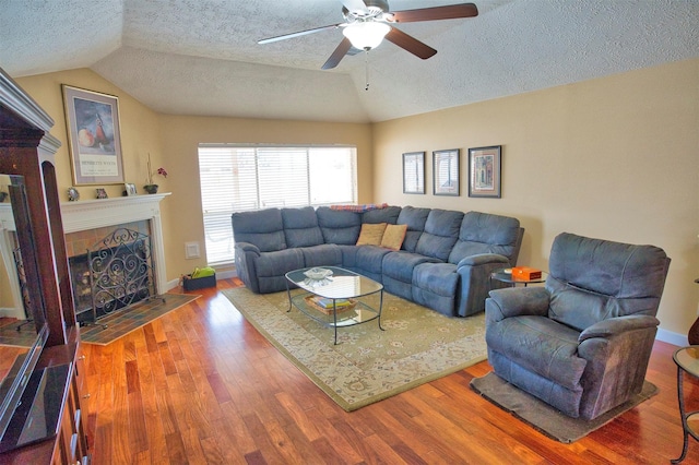 living room with lofted ceiling, a fireplace, wood-type flooring, and a textured ceiling