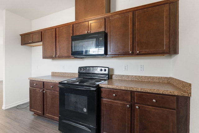 kitchen with dark hardwood / wood-style floors and black appliances