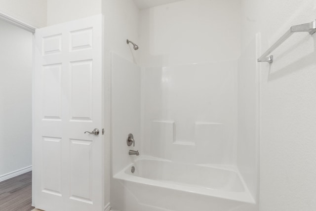 bathroom with hardwood / wood-style floors and washtub / shower combination