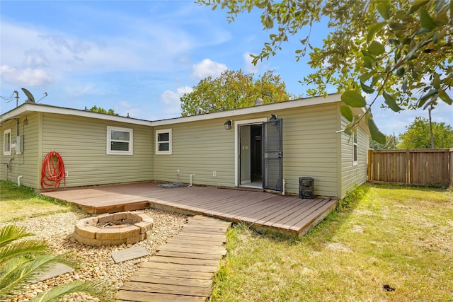 back of house with an outdoor fire pit, a deck, and a lawn