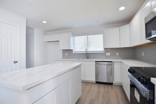 kitchen with appliances with stainless steel finishes, tasteful backsplash, sink, white cabinets, and light hardwood / wood-style floors