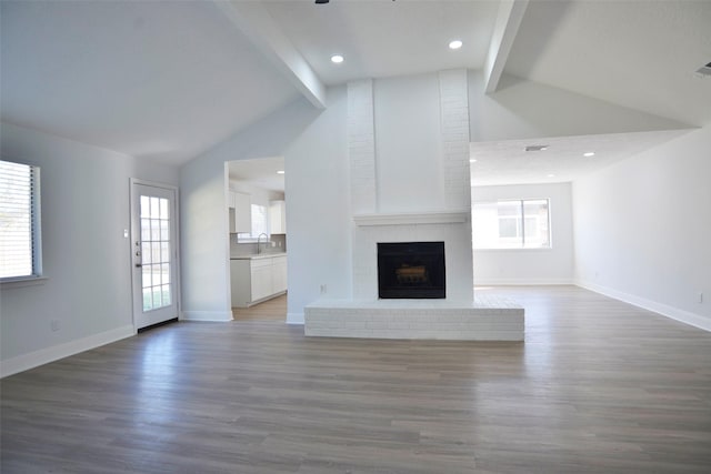 unfurnished living room featuring a healthy amount of sunlight, a fireplace, dark hardwood / wood-style flooring, and sink