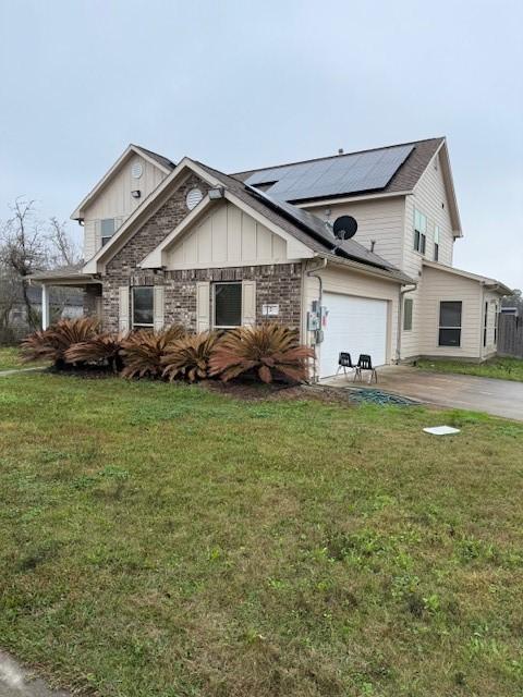 7 N Pine Rd, Texas City, TX 77591 - view of front of property featuring roof mounted solar panels, driveway, a front yard, and board and batten siding