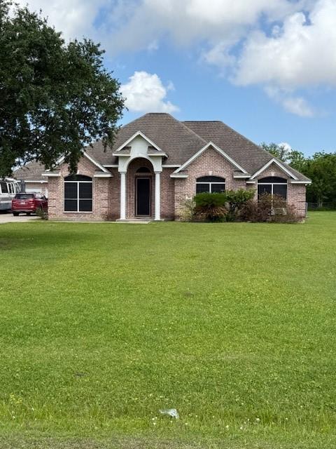 7 N Pine Rd, Texas City, TX 77591 - view of front facade with a front yard, roof with shingles, and brick siding