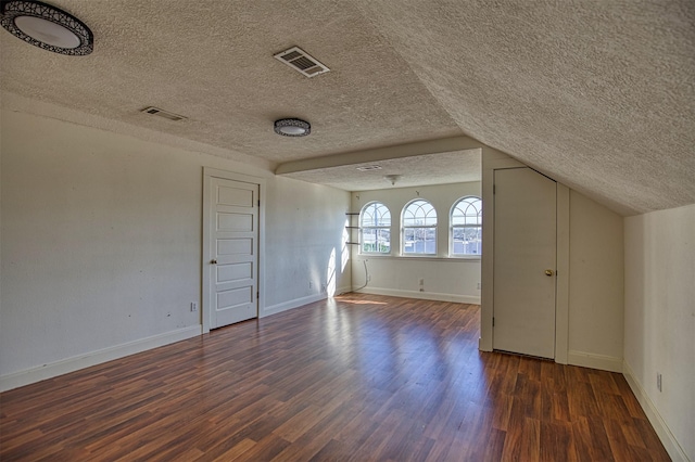 bonus room featuring lofted ceiling, dark wood-type flooring, and a textured ceiling