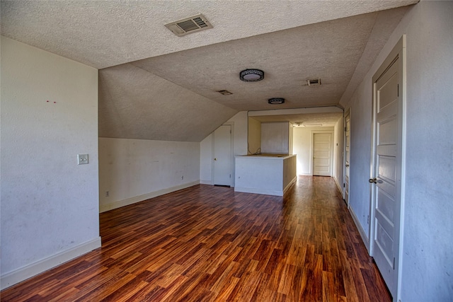 bonus room featuring lofted ceiling, dark hardwood / wood-style floors, and a textured ceiling