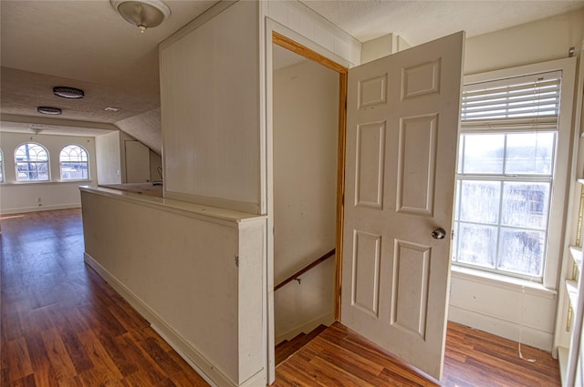 hallway with dark wood-type flooring and a textured ceiling