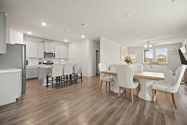 dining space with ceiling fan and light hardwood / wood-style flooring