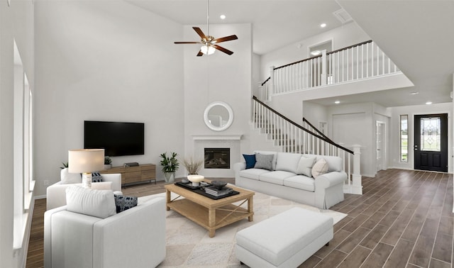 living room with a towering ceiling, hardwood / wood-style floors, and ceiling fan